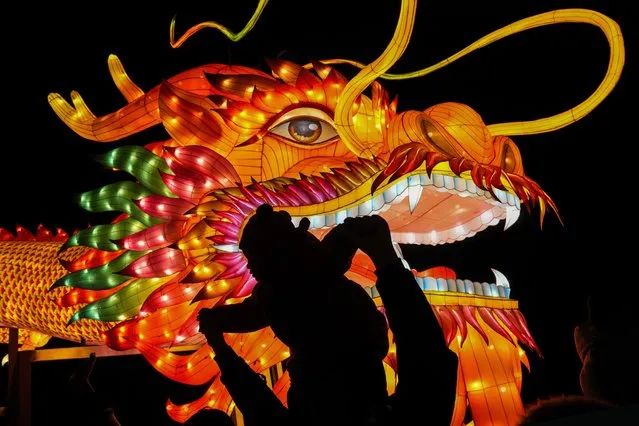 A man and a toddler are silhouetted as they pose for a souvenir photo with a giant dragon lantern decorated near the popular Houhai Lake in Beijing, Thursday, February 8, 2024. Chinese will celebrate Lunar New Year on Feb. 10 this year which marks the Year of the dragon on the Chinese zodiac. (Photo by Andy Wong/AP Photo)