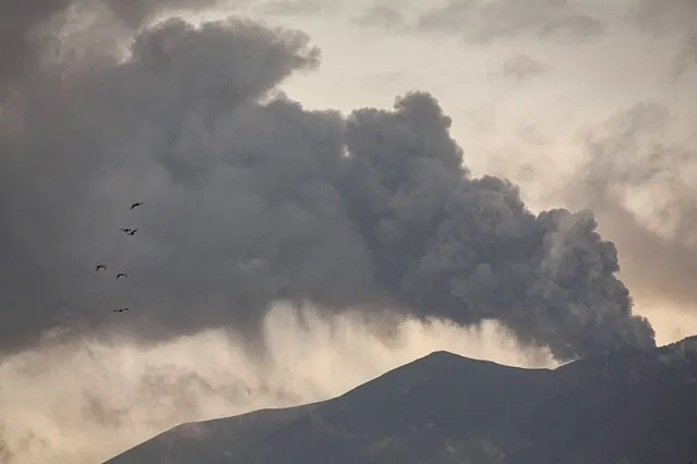 Mount Marapi spews volcanic materials during its eruption as seen from Tanah Datar, West Sumatra, Indonesia, Friday, December 22, 2023. Volcanic ash spewing from the nearly 2,900-meter (9,480-foot) volcano shut down airports and blanketed nearby communities on Sumatra island Friday. (Photo by Ali Nayaka/AP Photo)