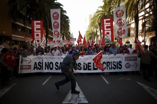 Workers and union members hold banners and flags of the General Workers Union (UGT) and Comisiones Obreras (CCOO) during a May Day rally in Malaga, Spain May 1, 2015. The banner reads, “This way we would not get out of the crisis”. (Photo by Jon Nazca/Reuters)