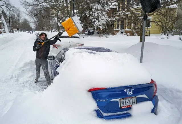 Christian Parker of Buffalo, N.Y., shovels out his car in the Elmwood Village neighborhood of Buffalo, N.Y. Monday, December 26, 2022, after a massive snow storm blanketed the city. Along with drifts and travel bans, many streets were impassible due to abandoned vehicles. (Photo by Craig Ruttle/AP Photo)