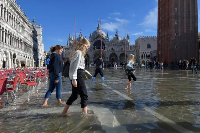 People walk in a flooded St. Mark's Square in Venice, Italy, Friday, November 5, 2021. After Venice suffered the second-worst flood in its history in November 2019, it was inundated with four more exceptional tides within six weeks, shocking Venetians and triggering fears about the worsening impact of climate change. (Photo by Luigi Costantini/AP Photo)