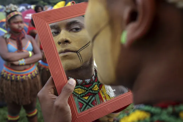A young indigenous man applies body paint as he checks himself out in a mirror, during an annual three-day campout protest known as the Free Land Encampment, in Brasilia, Brazil, Wednesday, April 24, 2019. The event begins amid animosity between Brazil’s indigenous groups and the new government of far-right President Jair Bolsonaro. (Photo by Eraldo Peres/AP Photo)