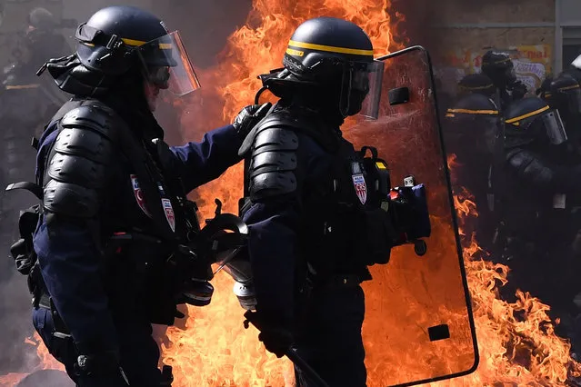 Anti-riot police walk past a buring barricade as they clash with protesters during a May Day demonstration in Paris, on May 1, 2019. Paris riot police fired teargas as they squared off against hardline demonstrators among tens of thousands of May Day protesters, who flooded the city in a test for France's zero-tolerance policy on street violence. (Photo by  Anne-Christine Poujoulat/AFP Photo)