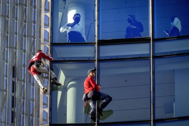 French urban climbers Alain Robert, left, well known as “Spiderman”, and Leo Urban climb up the Skyper high-rise building in central Frankfurt, Germany, as people watch from their office, Tuesday, November 23, 2021. (Photo by Michael Probst/AP Photo)