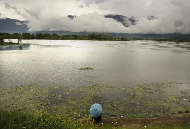 A Kashmiri man holds an umbrella as he fishes sitting on the banks of the Nigeen Lake on a rainy day in Srinagar, Indian controlled Kashmir, Monday, April 27, 2015. (Photo by Mukhtar Khan/AP Photo)