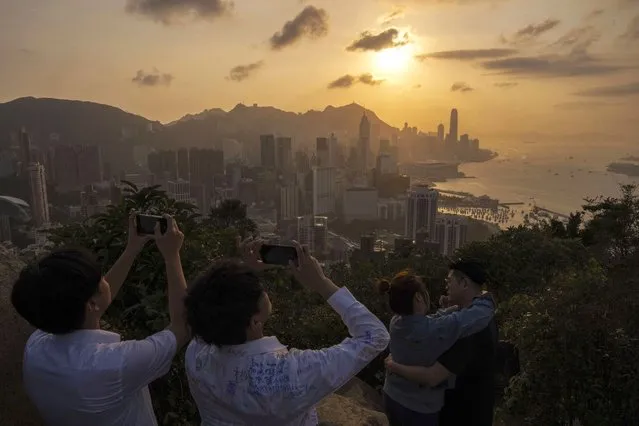 Visitors look at sunset from a hill in Hong Kong, Friday, March 22, 2024. (Photo by Louise Delmotte/AP Photo)