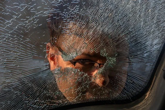 A Kashmiri man looks through the broken glass of a parked vehicle near the site of a shootout on the outskirts of Srinagar, Indian controlled Kashmir, Friday, December 31, 2021. Three suspected rebels were killed and four government forces wounded in a shootout early Friday, officials said, as violence increased in recent weeks. (Photo by Dar Yasin/AP Photo)
