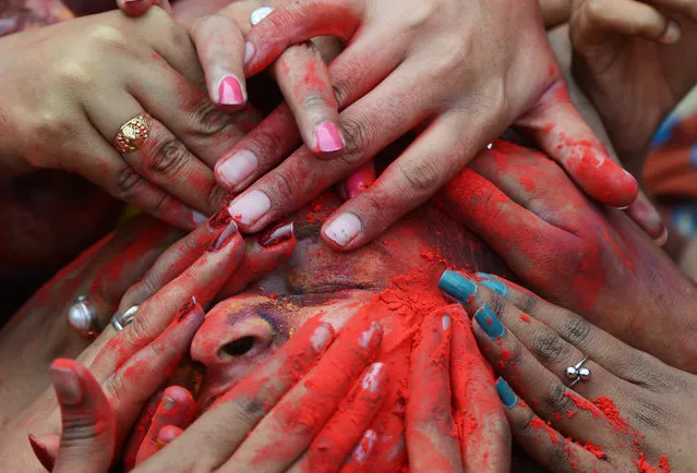 Indian students smear coloured powder at an event to celebrate the Hindu festival of Holi in Kolkata on March 7, 2017. Holi, the popular Hindu spring festival of colours is observed in India at the end of the winter season on the last full moon of the lunar month, and will be celebrated on March 13 this year. (Photo by Dibyangshu Sarkar/AFP Photo)