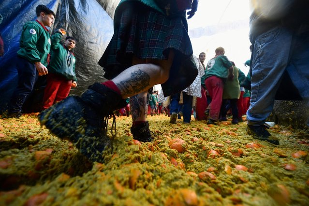 Revellers walk on smashed oranges as people participate in the annual 'Battle of the Oranges' in the northern city of Ivrea, Italy on February 19, 2023. (Photo by Massimo Pinca/Reuters)