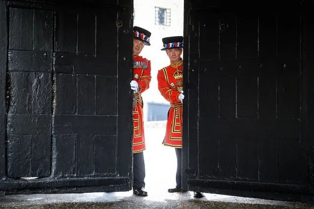 Yeoman Serjeant Clive Towel (L) and Yeoman Warder Darren Hardy pose with the gates at the main entrance during a photocall to promote the reopening of the Tower of London to the public on May 19, 2021 in London, England. After it's longest closure since World War Two, the Tower of London is reopening the 1,000 year old fortress. During lockdown, two new baby ravens were born, with a public vote open to decide the name of the female bird. Following the easing of lockdown restrictions on Monday, many tourist attractions, restaurants and venues have now opened their doors once more to the public. (Photo by Leon Neal/Getty Images)