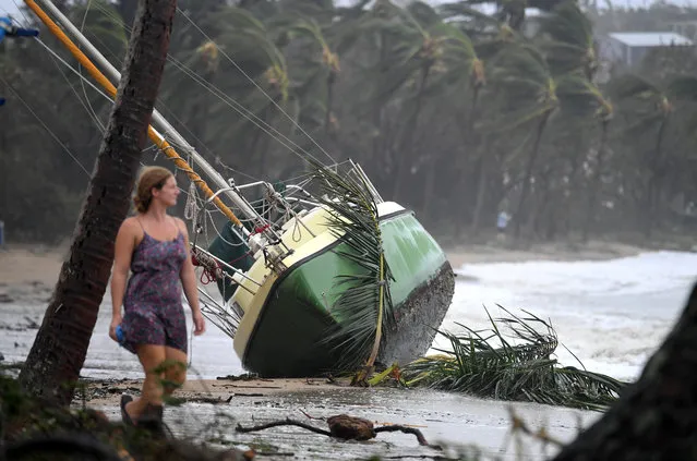 A local resident walks past a yacht that was washed ashore in Airlie Beach, Australia, Wednesday, March 29, 2017. (Photo by Dan Peled/Reuters/AAP)