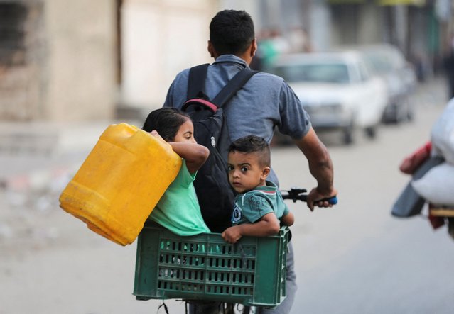 A Palestinian rides a bicycle with children along with their belongings as they flee Rafah due to an Israeli military operation, in Rafah, in the southern Gaza Strip, on May 28, 2024. (Photo by Hatem Khaled/Reuters)