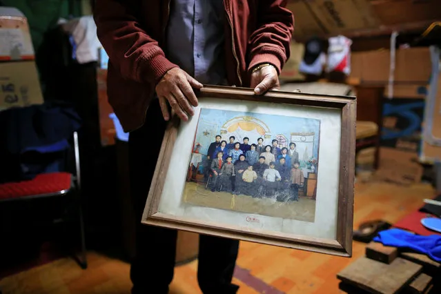 A man surnamed Xu, 50, holds a family portrait, at his place in Guangfuli neighbourhood, in Shanghai, China, April 8, 2016. Xu's whole family used to live under the same roof together in Guangfuli. (Photo by Aly Song/Reuters)