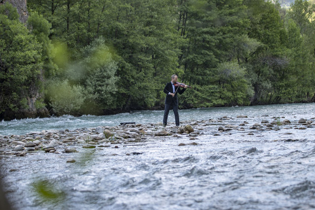 Ugur Cit, an academic living in Tunceli, plays the violin in the middle of the Munzur River to draw attention to the beauty of the Munzur Valley National Park in Tunceli, Turkiye on June 08, 2024. (Photo by Sidar Can Eren/Anadolu via Getty Images)