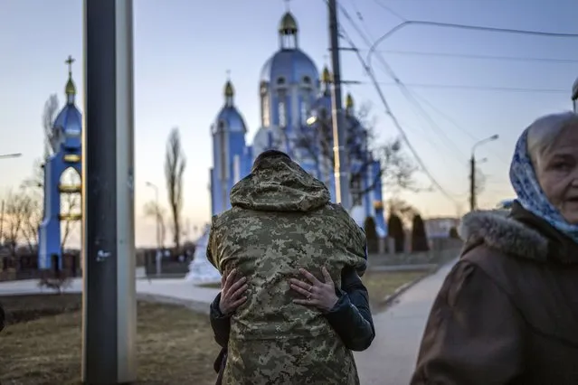 A soldier embraces a relative fleeing the war, minutes before departing by bus to Poland, in Vinnytsia, Ukraine, Wednesday, March 16, 2022. (Photo by Rodrigo Abd/AP Photo)