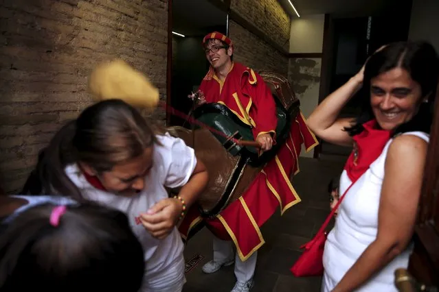 Women react as they are hit with a sponge by a “Zaldiko” (men wearing horse figures) during San Fermin festival's “Comparsa de gigantes y cabezudos” (Parade of Giants and Big Heads) in Pamplona, northern Spain, July 13, 2015. (Photo by Susana Vera/Reuters)