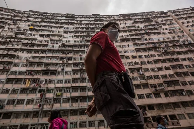 People walk past a residential building in Hong Kong on March 18, 2022. (Photo by Dale de la Rey/AFP Photo)
