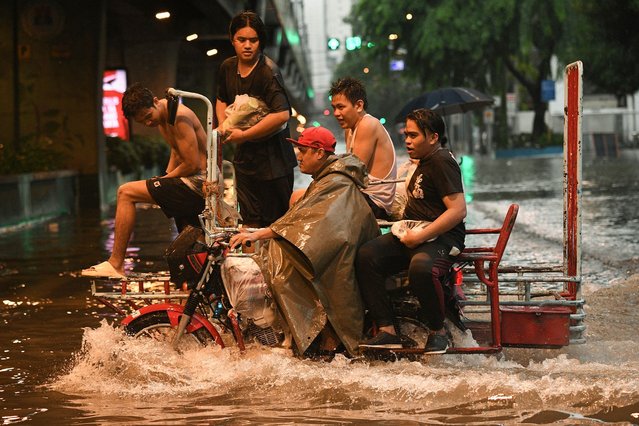 Motorists cross a flooded street in Manila on July 24, 2024 amid heavy rains brought by Typhoon Gaemi. (Photo by Ted Aljibe/AFP Photo)