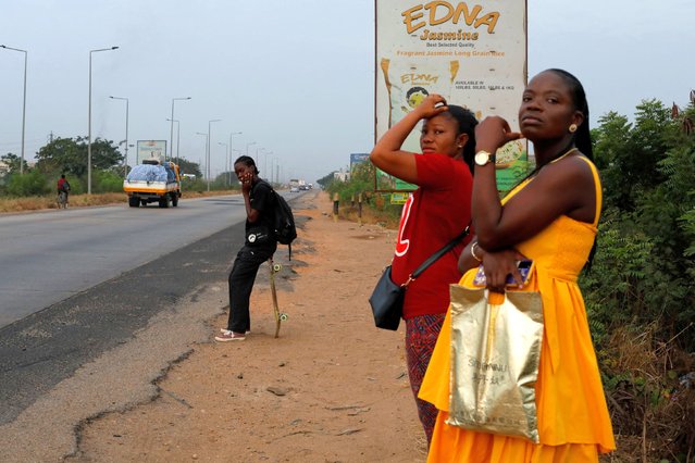 Harmonie Bataka, 27, a skateboarder and skateboarding tutor, waits to catch a bus to the Freedom Skatepark, in Tema, Ghana, March 5, 2022. Bataka quit her job last year to pursue the sport full time, to the dismay of friends and family. “They said there were too many boys doing it, boys who were too good for me to win any competitions . but I didn't care” she said. “I just wanted to be free to do what I love”. (Photo by Francis Kokoroko/Reuters)