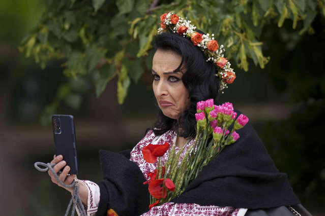 A woman wearing a Romanian traditional costume grimaces while takeing a selfie picture during an event celebrating the country's rural national outfits in Bucharest, Romania, Sunday, May 12, 2024. (Photo by Vadim Ghirda/AP Photo)