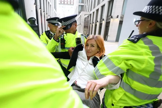 A detained Extinction Rebellion activist, who glued herself to the reception desk earlier, is carried out of the building by police during a protest at Shell's headquarters in London, Britain, April 13, 2022. (Photo by Hannah McKay/Reuters)