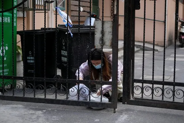 A resident checks plastic bags of food at a residential area under lockdown amid the coronavirus disease (COVID-19) pandemic, in Shanghai, China on April 17, 2022. (Photo by Aly Song/Reuters)