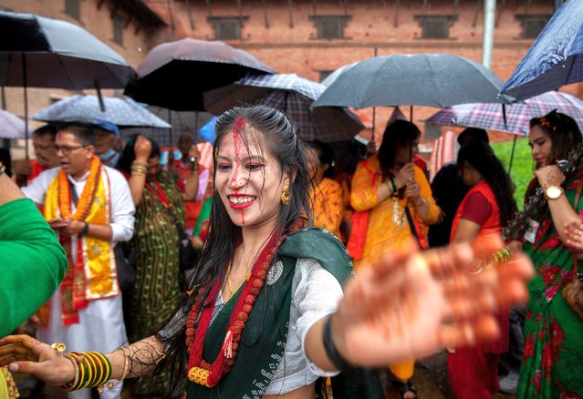 A Nepalese Hindu woman dances and sings during a Sarwan Brata offering after lighting lamps to Lord Shiva, the god of creation and destruction, at the Pashupati temple in Kathmandu, Nepal, 22 July 2024. Married and single Nepalese Hindu women gathered in temples on each Monday of the Sawan month, spanning from 22 July to 12 August, to pray for a long and prosperous life of their husbands or for a chance to find a good one. The fasting is undertaken every Monday exclusively by women worshipping Lord Shiva. (Photo by Narendra Shrestha/EPA/EFE)