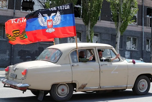 Service members of pro-Russian wave from a car during a ceremony, marking the 77th anniversary of the victory over Nazi Germany in World War Two, in the course of Ukraine-Russia conflict in the southern port city of Mariupol, Ukraine on May 9, 2022. (Photo by Alexander Ermochenko/Reuters)