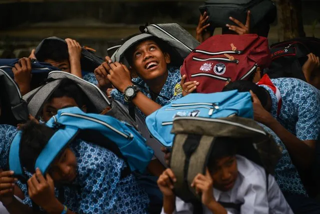 Students cover their heads during an earthquake and tsunami drill at their school in Banda Aceh on October 9, 2019. A huge 9.1 magnitude undersea quake in 2004 triggered a tsunami that killed more than 170,000 people in Aceh province, on western Sumatra island, and tens of thousands more in other countries with coasts on the Indian Ocean. (Photo by Chaideer Mahyuddin/AFP Photo)