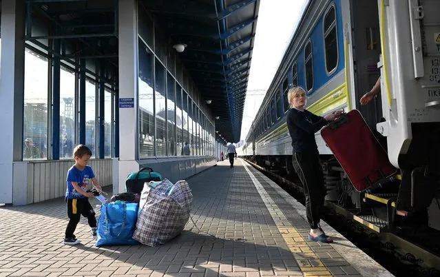 A woman and her child, one of the thousands of women and children who fled the Ukraine after Russia invaded, disembarks with her luggage upon their arrival from Poland, at Kyiv's railway station on May 12, 2022. For the first time since the start of the war, the flow was reversed on May 10 with 29,000 departures for 34,000 returns according to official figures from border guards, even if the balance remains largely negative overall with 5.9 million departures for 1.56 million back. Russia invaded Ukraine on February 24, 2022. (Photo by Sergei Supinsky/AFP Photo)