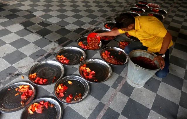 A Muslim man prepares plates of food for an Iftar (breaking of fast) meal inside a mosque on the first day of Ramadan in India, in Kolkata, India, June 7, 2016. (Photo by Rupak De Chowdhuri/Reuters)