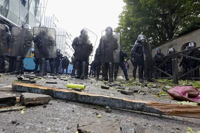 French gendarmes stand in line amongst debris in a street after clashes during a demonstration in Paris as part of nationwide protests against plans to reform French labour laws, France, June 14, 2016. (Photo by Jacky Naegelen/Reuters)