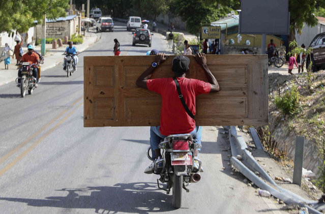 A man carries a wooden door on a motorcycle in Port-au-Prince, Haiti, Thursday, August 8, 2024. (Photo by Odelyn Joseph/AP Photo)