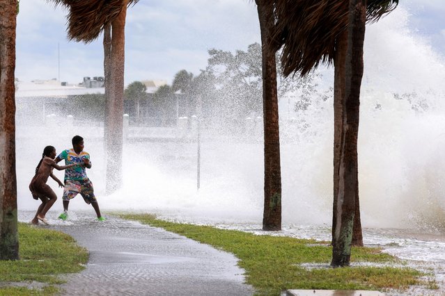 People are splashed by churning surf from Tampa Bay as Hurricane Helene passes offshore on September 26, 2024, in St. Petersburg, Florida. Helene is forecast to become a major hurricane, bringing the potential for deadly storm surges, flooding rain, and destructive hurricane-force winds along parts of the Florida West Coast. (Photo by Joe Raedle/Getty Images)