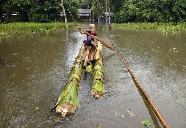 A boy rows a makeshift raft outside his submerged house in the flood-affected Kuthori village near Kaziranga National Park in Nagaon district, in the northeastern state of Assam, India, July 11, 2017. (Photo by Anuwar Hazarika/Reuters)
