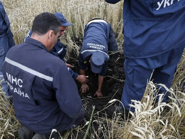 Members of the Ukrainian Emergency Ministry search for bodies near the site of Thursday's Malaysia Airlines Boeing 777 plane crash near the settlement of Grabovo, in the Donetsk region. (Photo by Maxim Zmeyev/Reuters)