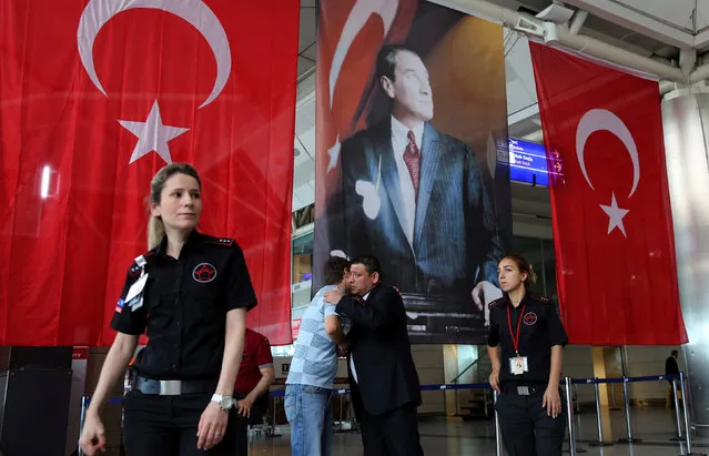 Men greet each other in front of Turkish flag and picture of modern Turkey's founder Mustafa Kemal Ataturk at Istanbul Ataturk airport, Turkey, following yesterday's blast June 29, 2016. (Photo by Goran Tomasevic/Reuters)