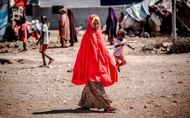 A girl walks towards her tent at a displacement camp for people affected by intense flooding in Beledweyne, Somalia, on December 14, 2019. The rains have inundated big areas surrounding Beledweyne area forcing thousands of people to leave their houses and look for humanitarian assistance while living in displacement camps. Due to climate change and human activities, cycles of floods and droughts have become more recurrent and completely unpredictable in Somalia exposing hundreds of thousands of people every year to vulnerability and displacement. (Photo by Luis Tato/AFP Photo)