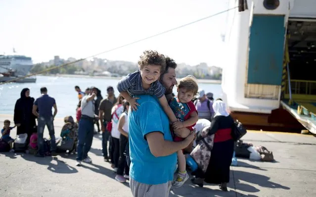 A Syrian refugee man plays with children following their arrival onboard “Eleftherios Venizelos” passenger ship at the port of Piraeus near Athens, Greece, August 20, 2015. (Photo by Stoyan Nenov/Reuters)