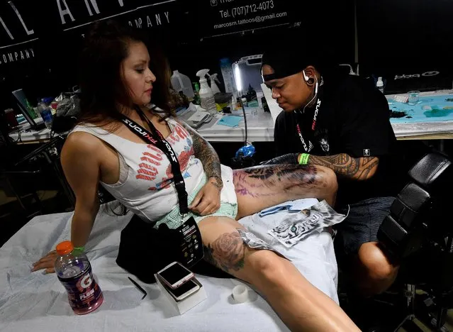 Tattoo artist Justin Param works on a tattoo for Dolly Rios at the LA Tattoo Convention in Long Beach, California, on August 19, 2017. Tattoo lovers  have been showing off their impressive inkings at annual conventions in LA and Russia this weekend. This year marks the sixth Siberian Tattoo Festival in Novosibirsk, Russia, while stateside tattoo fanatics have been celebrating all things body-art at the LA Tattoo Convention in Long Beach, California. (Photo by Mark Ralston/AFP Photo)