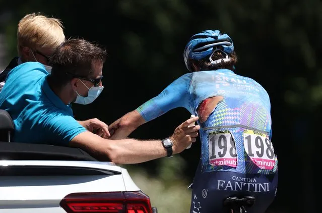 Israel-Premier Tech team's Canadian rider Michael Woods, with visible injuries seen through his torn jersey, receives medical treatment as he cycles after suffering a crash during the 9th stage of the 109th edition of the of the Tour de France cycling race, 192,9 km between Aigle in Switzerland and Chatel Les Portes du Soleil in the French Alps, on July 10, 2022. (Photo by Thomas Samson/AFP Photo)