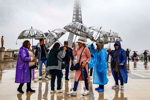 Visitors shelter from the rain with umbrellas on the Parvis des Droits de l'Homme on Esplanade du Tocadero across from the Eiffel Tower, as remnants of hurricane Kirk cause heavy rainfall over Paris, on October 9, 2024. (Photo by Ludovic Marin/AFP Photo)