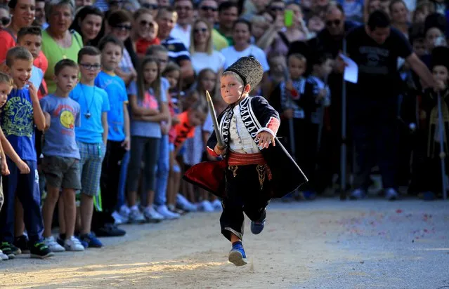 Alkar Vito runs during the Children's Alka competition in Vuckovici village, Croatia, August 23, 2015. Children's Alka is a tournament which has been held every August in the Croatian village of Vuckovici since 1955, commemorating the victory over the Ottoman Turkish administration. The tournament is named after the ring, Alka, which children have to hit with their spears. (Photo by Antonio Bronic/Reuters)