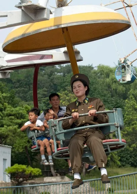 A female members of the Korean People's Army rides on a fairground ride in Pyongyang, North Korea, undated. Members of the Korean People's Army relax on a roller coaster in these unseen images. French photographer Eric Lafforgue, 47, took the snaps during six trips to the secretive state. He managed to capture the softer side of the foot soldiers usually seen snarling in photographs sent around the world.  (Photo by Eric Lafforgue/Barcroft Media)