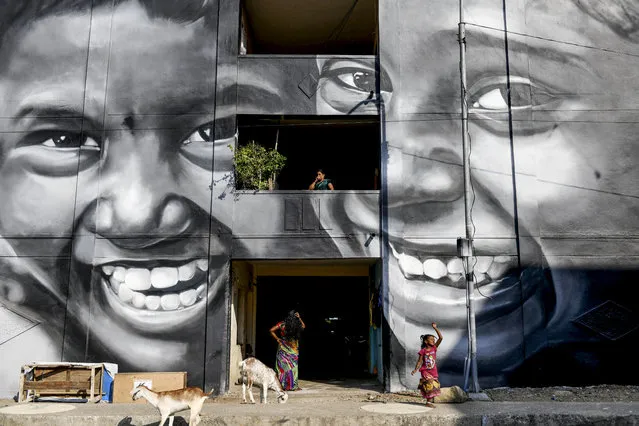 Residents walk past a mural painted on a building at a slum clearance board residential community in Chennai on February 18, 2020. (Photo by Arun Sankar/AFP Photo)