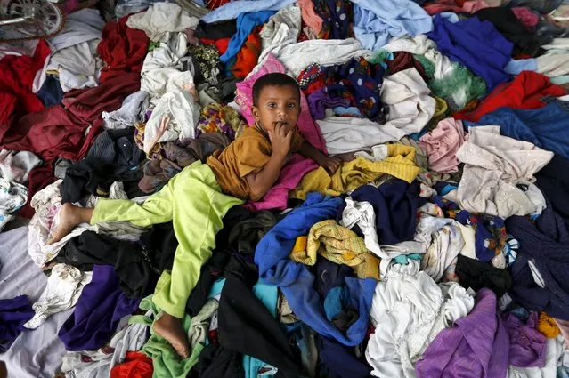 A girl plays on clothes donated by local people for charity outside her makeshift home in New Delhi, India, August 17, 2015. (Photo by Adnan Abidi/Reuters)