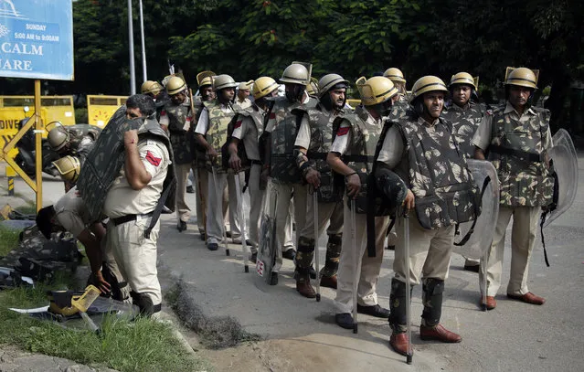 An Indian policeman puts on a bullet proof vest as he joins others on a road leading to a court in Panchkula, India, Friday, August 25, 2017. Several north Indian cities were under a security lock down Friday as a court was expected to issue a verdict in a rape case involving a man who calls himself Saint Dr. Gurmeet Ram Rahim Singh Ji Insan, the flamboyant leader of a quasi-religious sect. (Photo by Altaf Qadri/AP Photo)