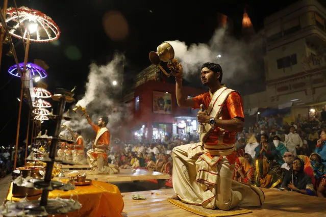 Hindu devotees watch as priests perform rituals during a prayer ceremony dedicated to holy river Ganges in Varanasi, India, Friday, March 6, 2020. India is bracing for a potential explosion of coronavirus cases as authorities rush to trace, test and quarantine contacts of 31 people confirmed to have the disease. Prime Minister Narendra Modi's government said last week that community transmission is now taking place. India has shut schools, stopped exporting key pharmaceutical ingredients and urged state governments to cancel public festivities for Holi, the Hindu springtime holiday in which people douse each other with colored water and paint. (Photo by Rajesh Kumar Singh/AP Photo)