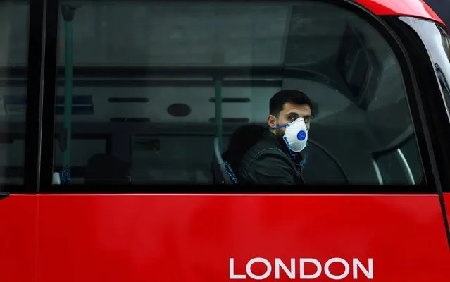 A man wears a mask while sitting on a bus, as the number of coronavirus cases grow around the world, in central London, Britain on March 14, 2020. (Photo by Dylan Martinez/Reuters)