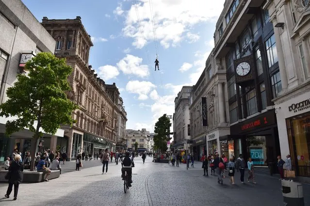 A member of the public rides a zip wire that has been built above one of the main shopping streets in Liverpool, north-west England on August 11, 2014. The 1000ft long wire will be open until September 7. (Photo by Paul Ellis/AFP Photo)